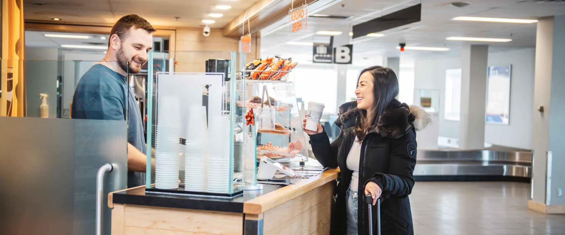 The image features a woman standing at a Javaroma, talking to a man who is working behind the counter.