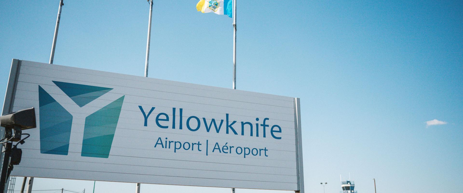 The image features a large sign for Yellowknife Airport, which is situated in front of a building.